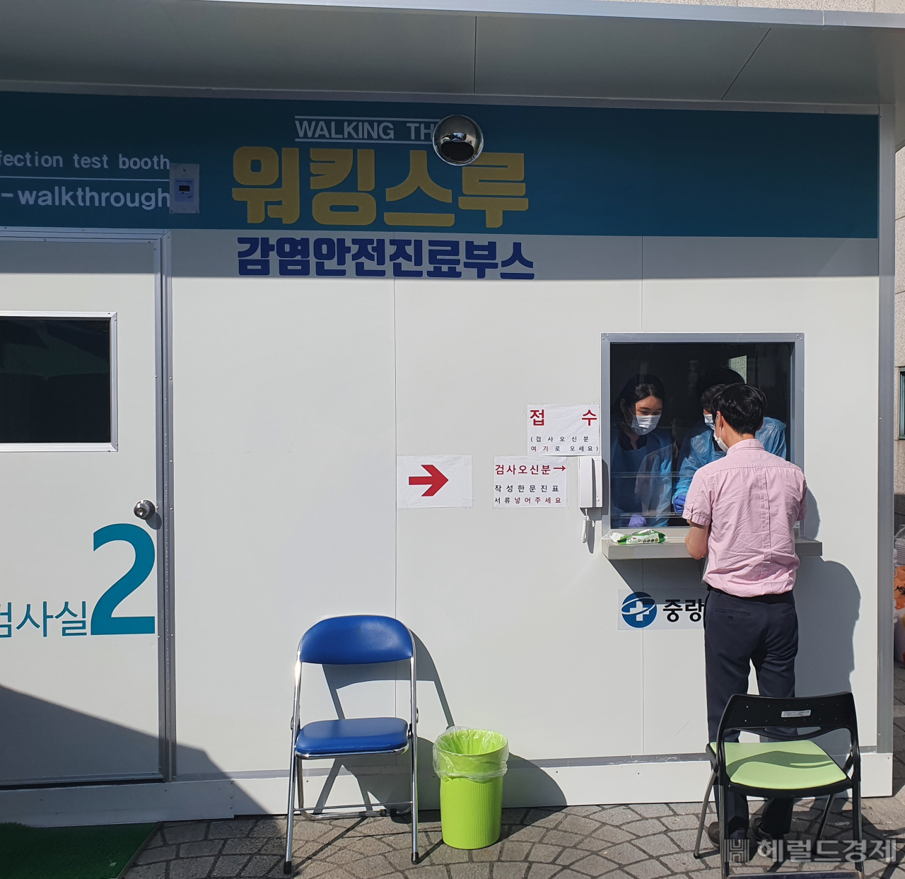 12일 중랑구 워킹스루 선별진료소에서 한 구민이 코로나 19 검사를 받고 있다. 서울 중랑구는 코로나19 선별진료소에서 근무하는 의료진을 보호하고 보다 안전한 검사를 진행하기 위해 워킹스루 선별진료소를 도입 운영하고 있다. 기존 선별진료소는 최근 폭염 발생으로 방호복 착용에 따른 탈진의 위험이 있고, 검사 과정에서 피검사자와 의료진이 직접 접촉해 감염의 우려가 발생하는 등 문제점이 있었다.이번에 설치한 워킹스루 선별진료소는 음압장비가 설치된 2개의 검체채취실과 1개의 사례분류 공간으로 구성돼 있으며 검사실 구멍을 통해 팔을 뻗어 검채를 채취하는 글로브-월(Glove-Wall) 시스템 방식이다.[중랑구 제공]
