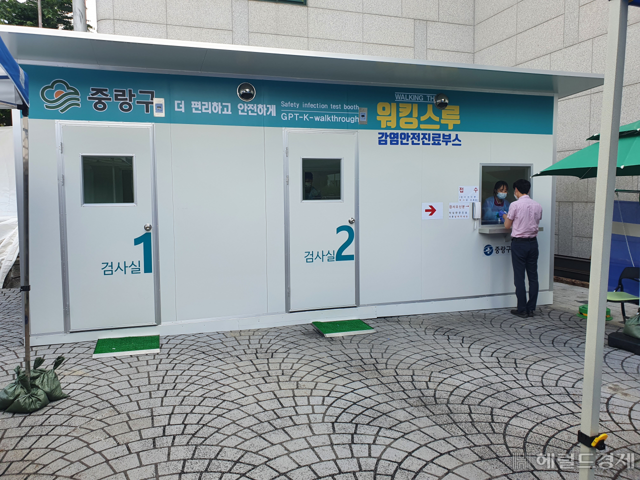 12일 중랑구 워킹스루 선별진료소에서 한 구민이 코로나 19 검사를 받고 있다. 서울 중랑구는 코로나19 선별진료소에서 근무하는 의료진을 보호하고 보다 안전한 검사를 진행하기 위해 워킹스루 선별진료소를 도입 운영하고 있다. 기존 선별진료소는 최근 폭염 발생으로 방호복 착용에 따른 탈진의 위험이 있고, 검사 과정에서 피검사자와 의료진이 직접 접촉해 감염의 우려가 발생하는 등 문제점이 있었다.이번에 설치한 워킹스루 선별진료소는 음압장비가 설치된 2개의 검체채취실과 1개의 사례분류 공간으로 구성돼 있으며 검사실 구멍을 통해 팔을 뻗어 검채를 채취하는 글로브-월(Glove-Wall) 시스템 방식이다.[중랑구 제공]