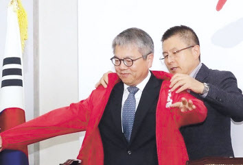 김용하 순천향대 IT금융경영학과 교수가 지난해 10월31일 국회에서 열린 ‘제1차 영입인재 환영식’에서 황교안 당시 자유한국당 대표로부터 점퍼를 받고 있다.  [연합]