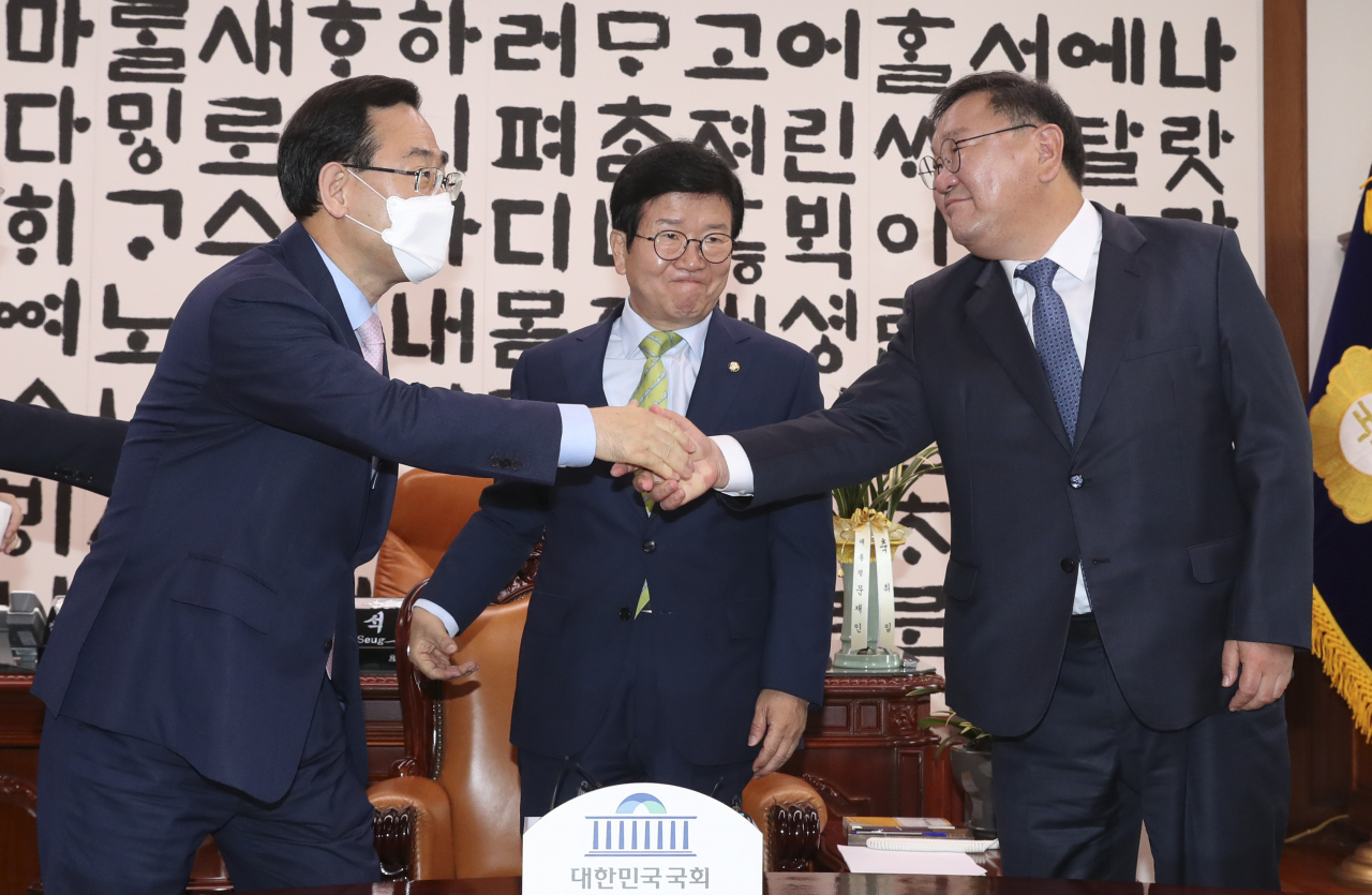 더불어민주당 김태년 원내대표(오른쪽)와 미래통합당 주호영 원내대표(왼쪽)가 이 11일 오전 서울 여의도 국회 국회의장실에서 열린 21대 국회 전반기 원구성 협상을 위한 국회의장 주재 원내대표 회동에서 악수하고 있다. 가운데는 박병석 국회의장. [연합]