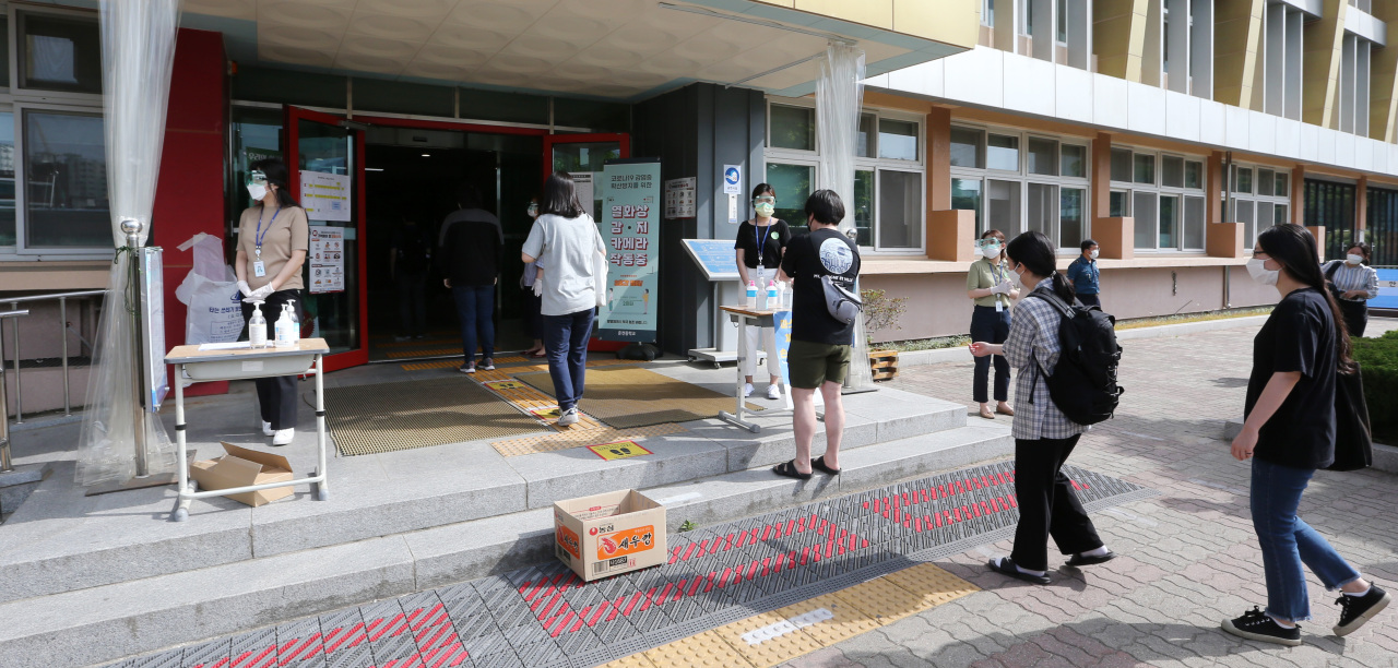 Applicants disinfect their hands before entering the test venue on Saturday. (Yonhap)