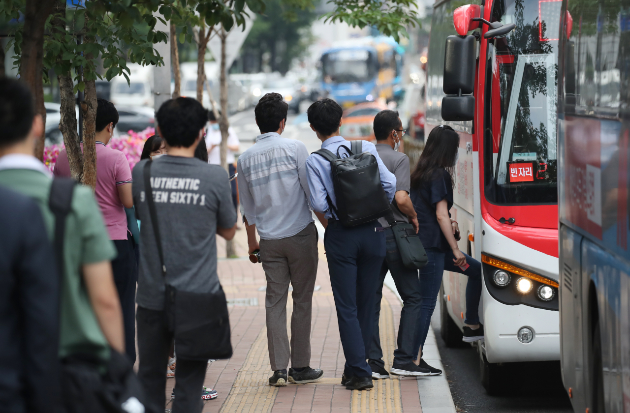 서울 중구의 한 버스 정류장에서 마스크를 쓴 시민들이 출근을 서두르고 있다. [연합]
