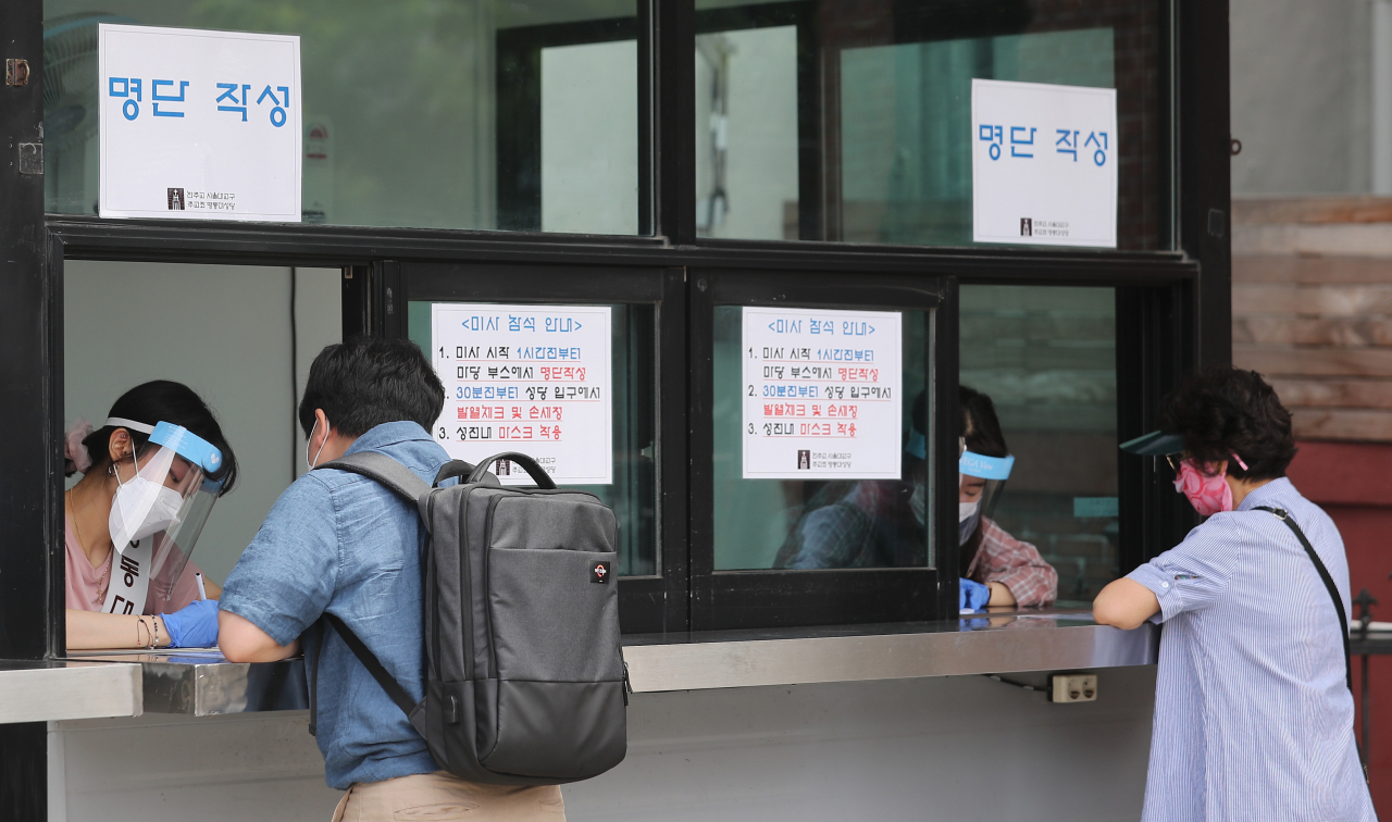 수도권에 집중된 신종 코로나바이러스 감염증(코로나19) 집단발병 여파가 계속되는 14일 오전 서울 명동성당에서 신자들이 미사 입장을 위해 명단을 작성하고 있다. [연합]