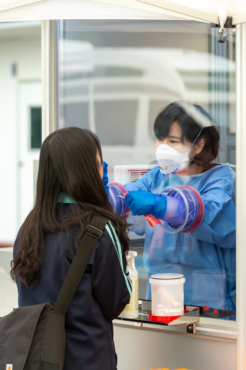 선별진료소 내부 의료진이 '글로브 월'을 이용해 바깥 쪽 피검자의 조직을 채취하고 있는 모습. [양천구 제공]