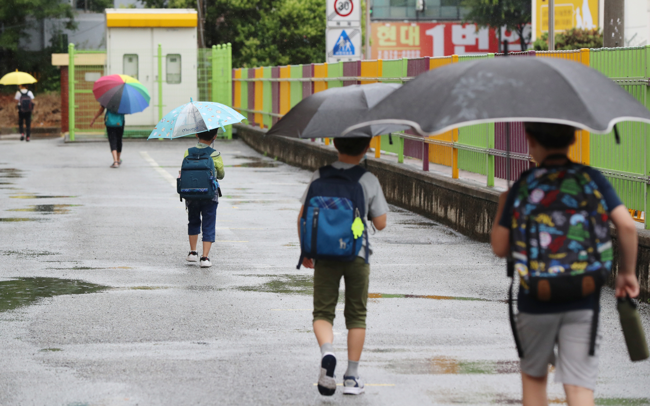 광주·전남지역에 비가 내린 지난 18일 오전 광주 북구 오치초등학교에서 학생들과 병설유치원생들이 마스크를 쓰고 코로나19 예방 발열체크를 하기 위해 줄지어 이동하고 있다. [연합]