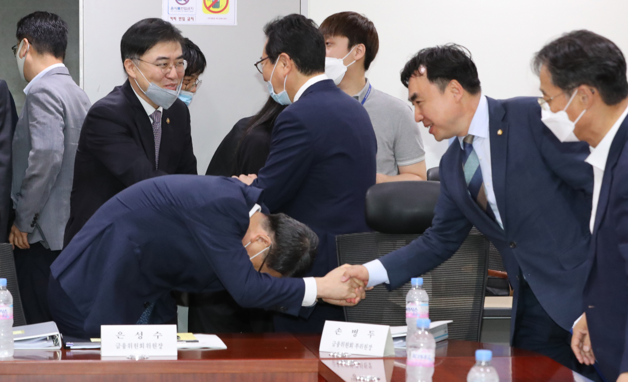 [사진=은성수 금융위원장이 18일 오전 서울 여의도 국회 의원회관에서 열린 정무위원회 업무보고에 참석하며 더불어민주당 윤관석 의원과 악수하고 있다.] [연합]