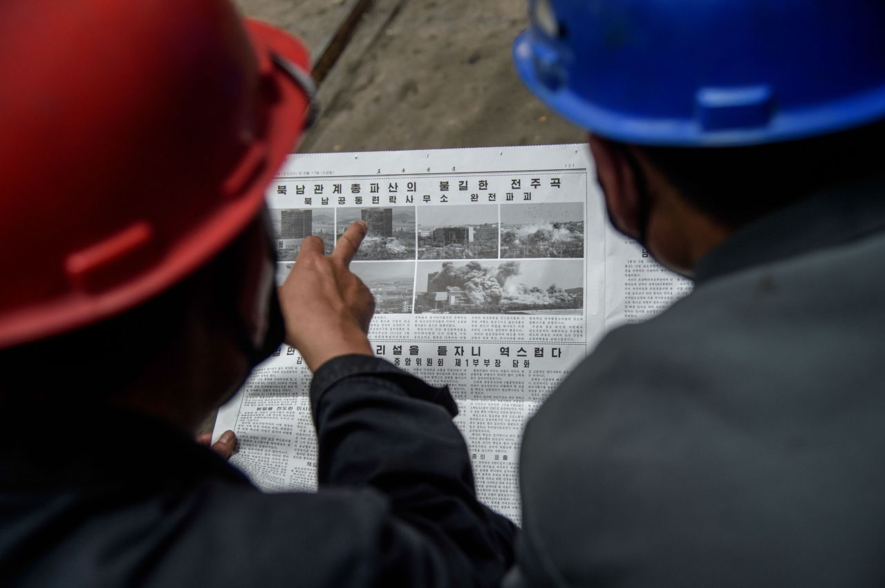 Employees of the Kim Jong Thae Electric Locomotive Complex in Pyongyang read a copy of the Rodong Sinmun newspaper showing coverage of North Korea's demolition of the north-south joint liaison office, on June 17, 2020. - North Korea's spectacular destruction of its liaison office with the South is part of a series of staged provocations aimed at forcing concessions from Seoul and Washington, analysts say. (AFP-Yonhap)