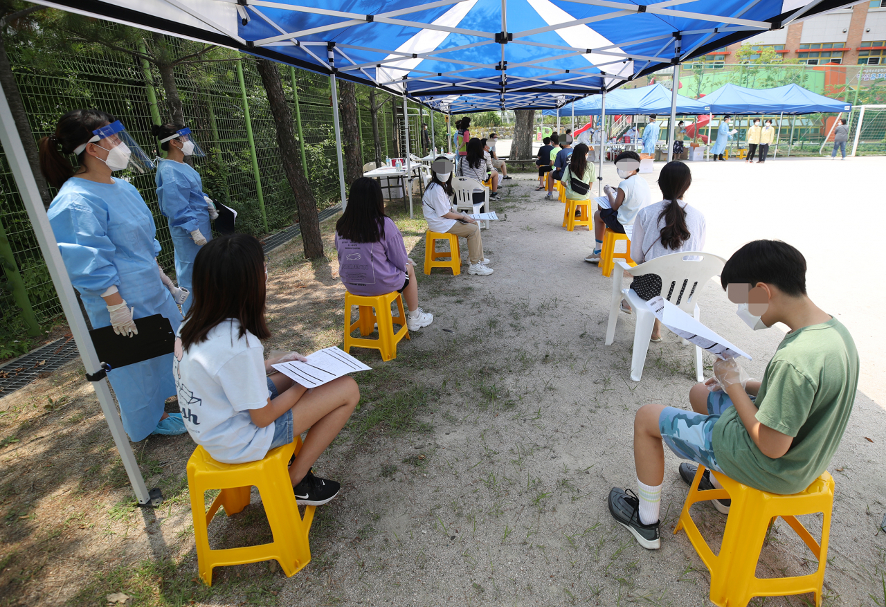 20일 오후 서울 성동구 옥수초등학교 운동장에 설치된 선별진료소에서 이 학교 6학년 학생, 교직원들이 코로나19 검사를 받기 위해 대기하고 있다. 성동구에 따르면 옥수초등학교 6학년생인 12세 어린이(여·성동 49번)와 그 외할머니인 60대 여성(성동 48번)이 전날 오후 검사를 받아 이날 확진됐다. 성동 49번 어린이는 17일 오전 8시께 등교해 졸업사진을 촬영했다. [연합]