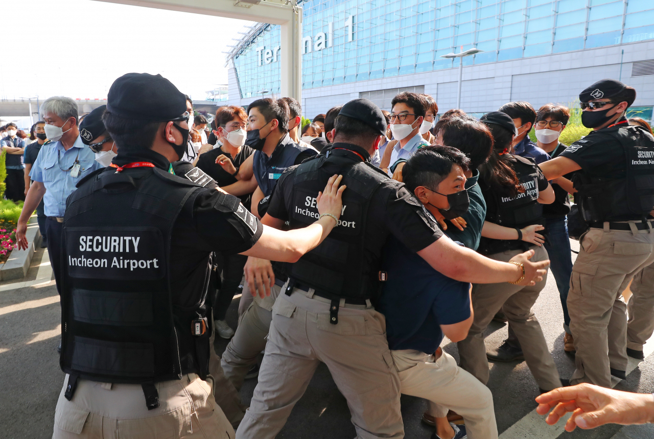 22일 인천국제공항 제1여객터미널에서 직원들이 보안검색 노동자 정규직화 관련 브리핑을 위해 브리핑룸으로 이동하는 구본환 인천국제공항공사 사장을 향해 항의하고 있다. [연합]
