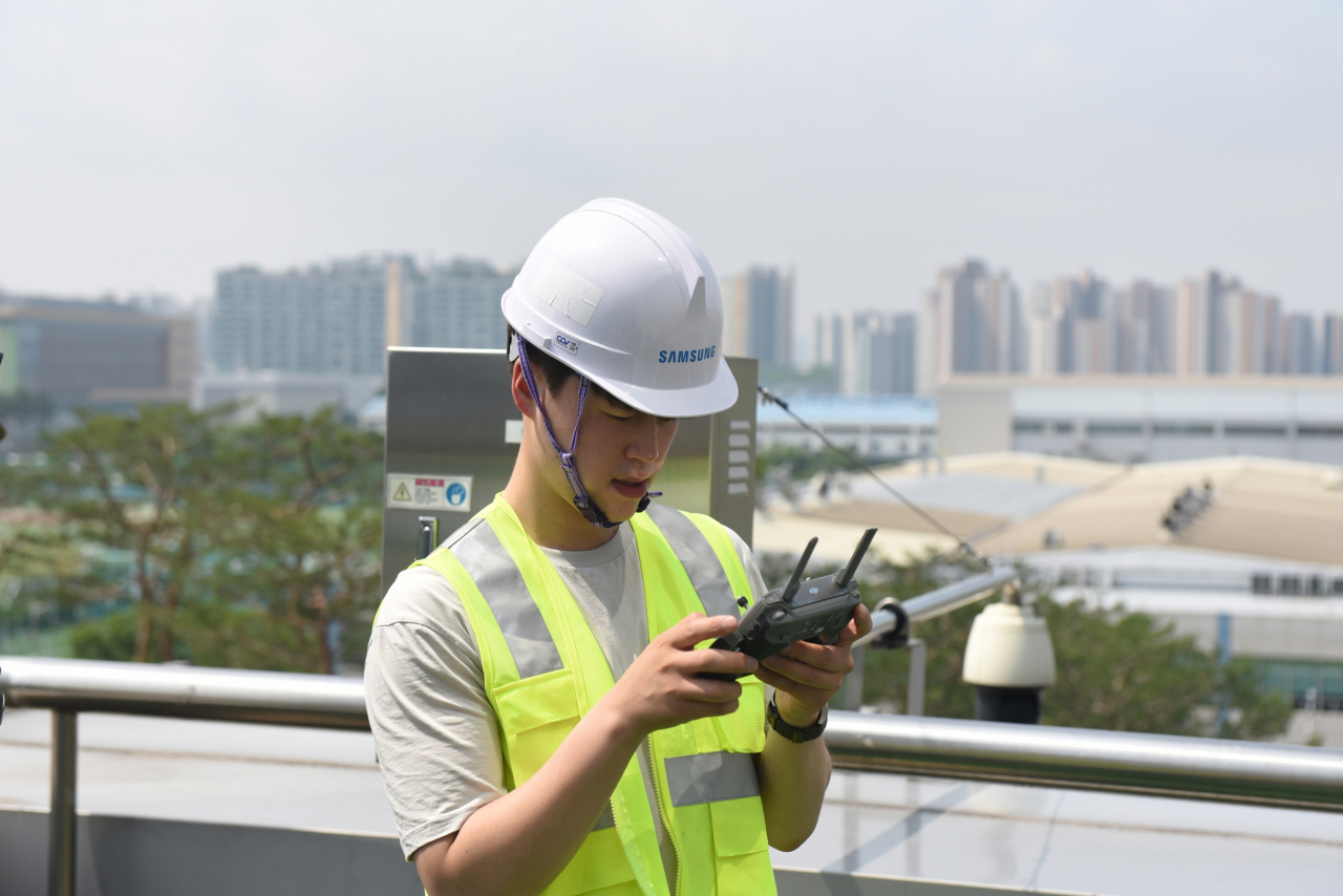 삼성 5G 네트워크 성능 최적화 솔루션 개발자가 기지국과 안테나 각도 측정을 위해 원격에서 드론을 조종하고 있는 모습 [삼성전자 제공]