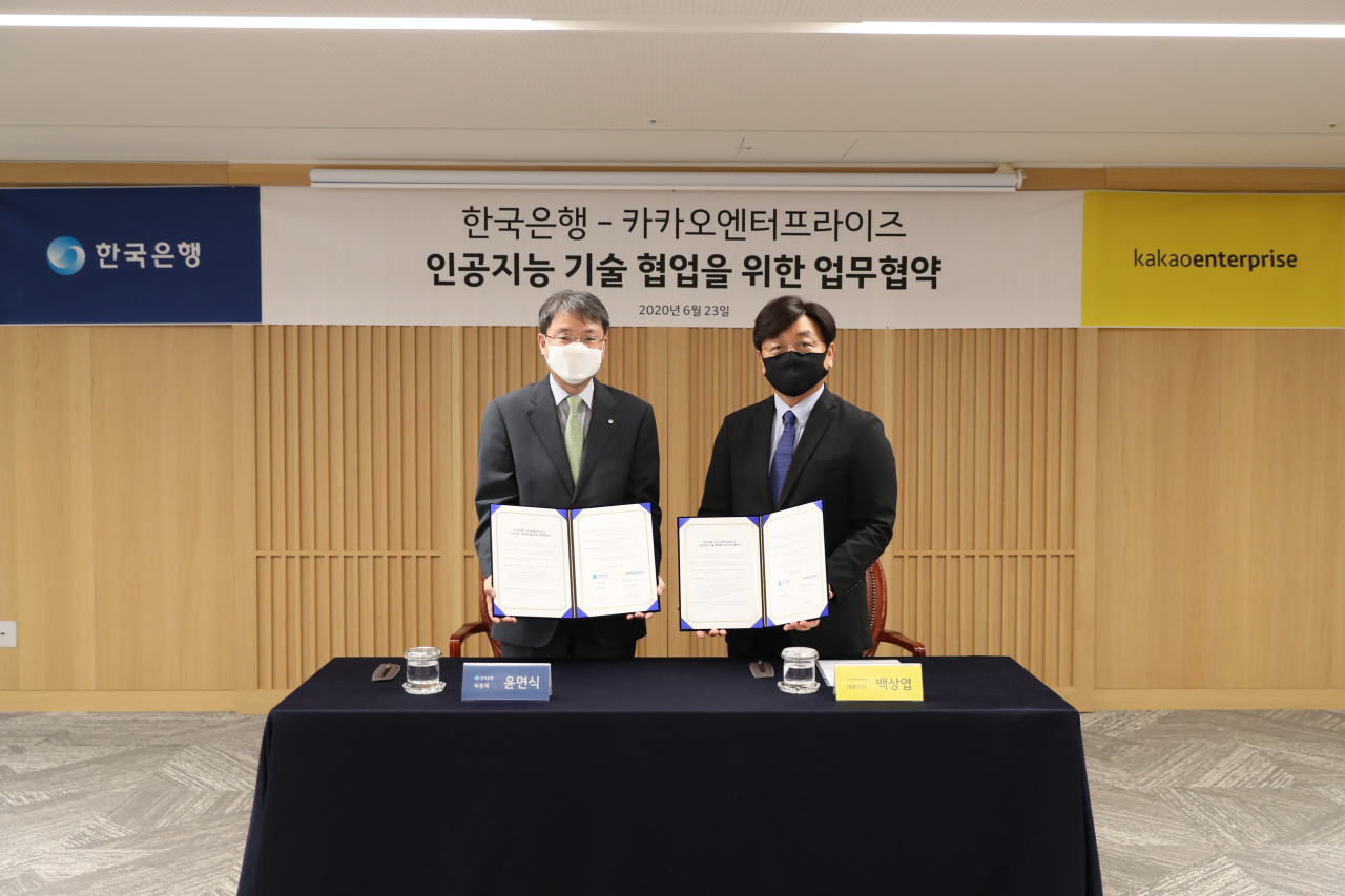 BOK Deputy Gov. Yoon Myun-shik (lef) and Kakao Enterprise CEO Baek Sang-yeop (right) pose for a photo at the central bank's headquarters in Seoul on Tuesday. (Bank of Korea)