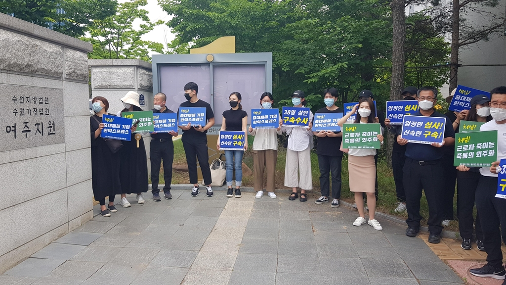 지난 23일 수원지법 여주지원 앞에서 이천 물류창고 화재 유가족들이 구속 수사를 촉구하는 팻말을 들고 있다. [연합]