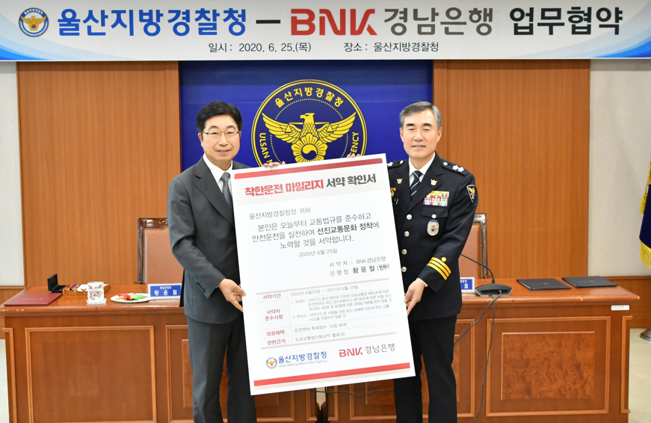25일 BNK경남은행 황윤철 은행장(사진 왼쪽)과 울산지방경찰청 김진표 청장이 ‘사람이 보이면 일단, 멈춤! 등 선진 교통문화 확산을 위한 업무 협약’을 체결한 뒤 기념촬영을 하고 있다