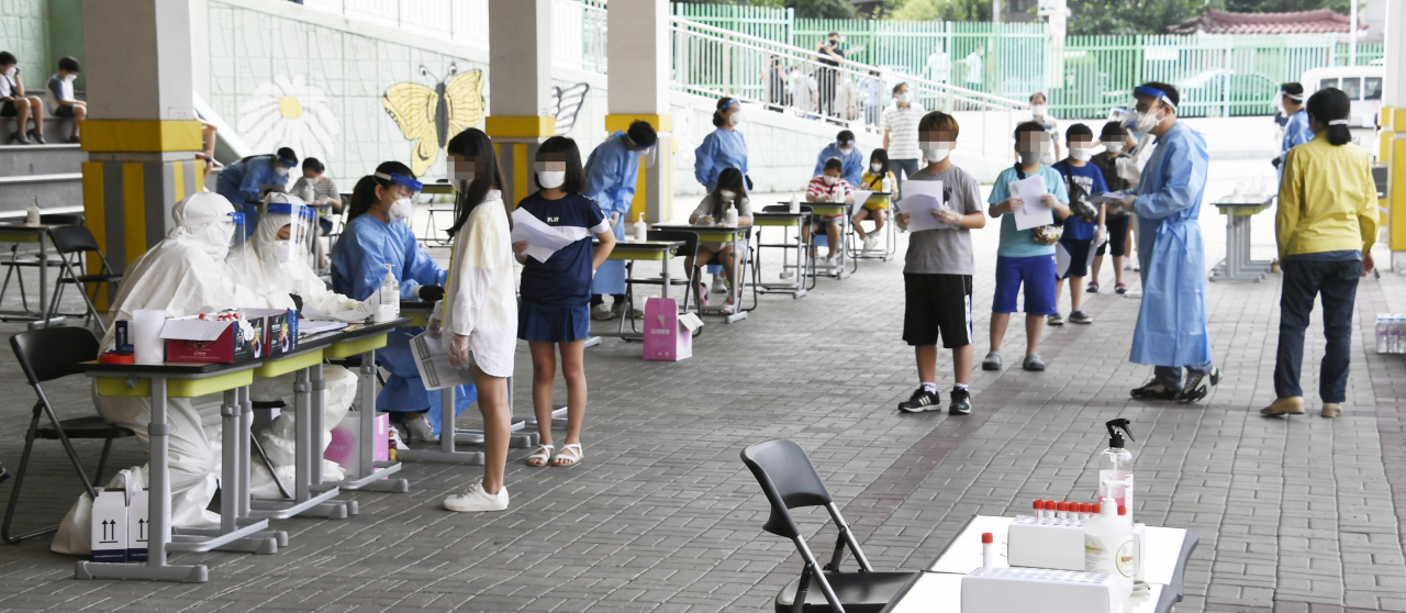 28일 서울 관악구 난우초등학교에 마련된 선별진료소에서 학생들이 코로나19 검사를 받기 위해 기다리고 있다. 왕성교회 신도 중 난우초등학교 시간강사가 확진 판정을 받아 난우초는 오는 29일 하루 등교를 중지키로 했다. [연합]