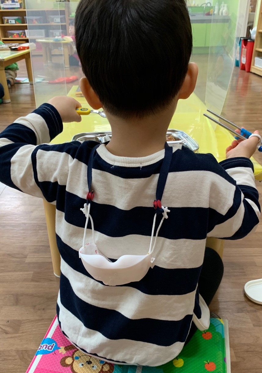 마스크 분실방지용 목걸이를 착용하고 식사를 하는 유치원생.
