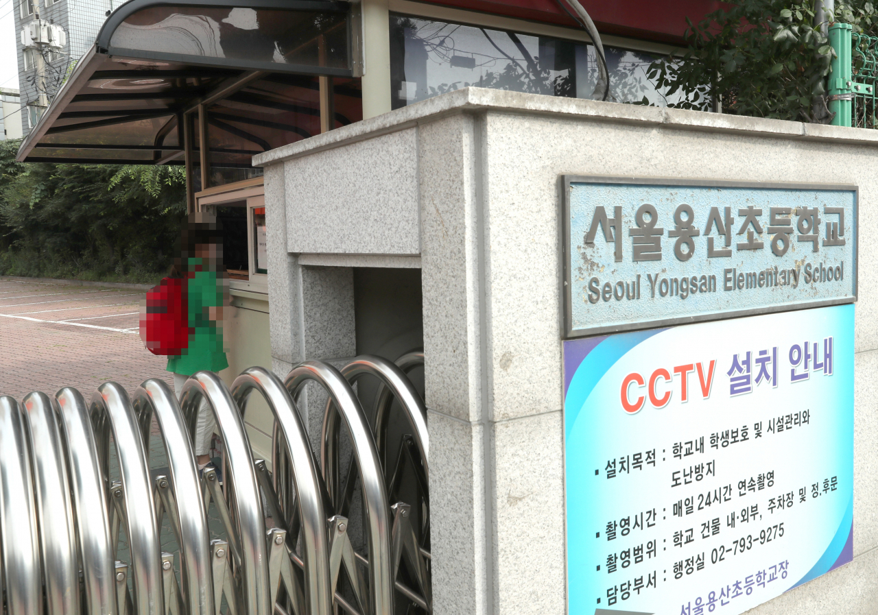 서울 용산초등학교가 국방부 어린이집에서 코로나19 확진자가 발생한 상황에 선제적으로 대응하고자 등교를 중지한 29일 서울 용산초등학교에서 한 학생이 학교보안관에게 등교 여부를 묻고 있다. [연합]