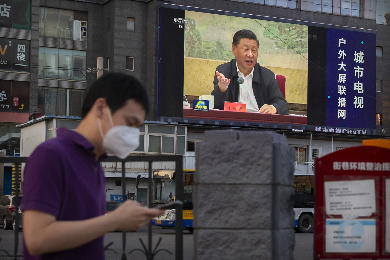 미국 백악관 국가안보회의(NSC)가 30일(현지시간) 홍콩국가보안법 시행 관련, “미국은 홍콩의 자유와 자치를 질식시킨 사람들에 대해 계속해서 강력한 조치를 취할 것”이라고 밝혔다. 중국 측이 전광석화처럼 보안법 시행을 감행하자 강경 대응을 천명한 것이다. 마스크를 낀 베이징 시민이 시진핑 중국 국가주석의 모습이 나온 전광판 아래에서 휴대폰을 보며걸어가고 있다. [AP]
