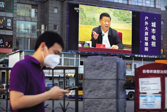 미국 백악관 국가안보회의(NSC)가 6월 30일(현지시간) 홍콩국가보안법 시행과 관련해 “미국은 홍콩의 자유와 자치를 질식시킨 사람들에 대해 계속해서 강력한 조치를 취할 것”이라고 밝혔다. 중국 측이 전광석화처럼 보안법 시행을 감행하자 강경 대응을 천명한 것이다. 마스크를 낀 베이징 시민이 시진핑 중국 국가주석의 모습이 나온 전광판 아래에서 휴대전화를 보며 걸어가고 있다. [AP]