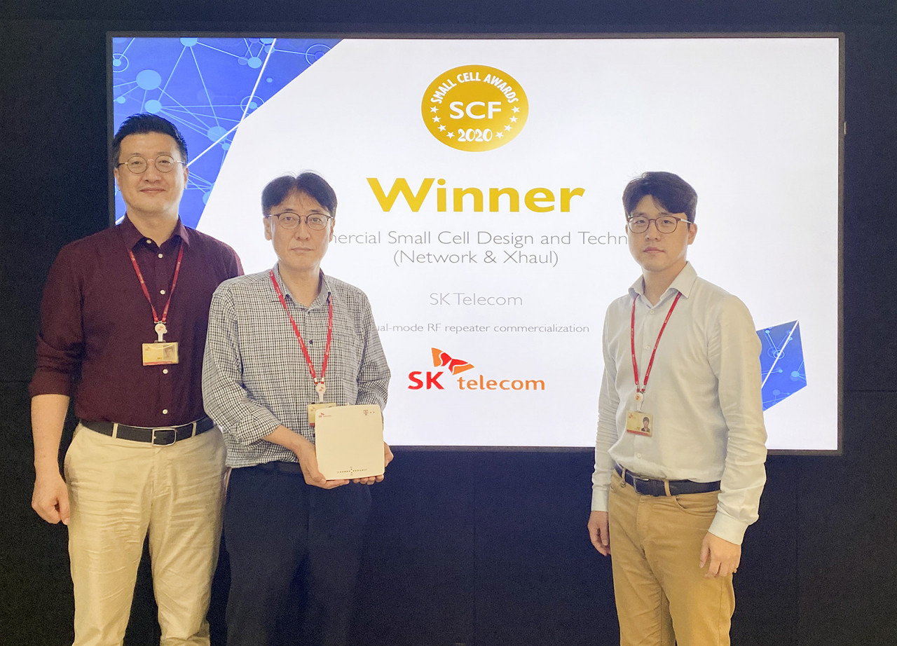 류탁기 SK텔레콤 Access Network개발팀 리더(왼쪽 첫번째)와 직원들이 스몰셀어워드에서 수상한 듀얼 모드 RF 중계기를 들고 스몰셀 어워드 수상 화면 앞에서 기념 촬영을 하고 있다.