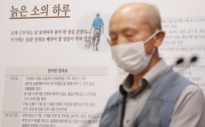 지난달 24일 오전 서울시청 브리핑룸에서 열린 ‘서울시 경비노동자 종합지원대책’ 기자설명회에 참석한 정의헌 전국아파트 경비노동자 공동사업단 대표 뒤로 조정진 작가의 ‘임계장 이야기’ 일부가 전시돼 있다. 임계장은 ‘임시 계약직 노인장’의 준말로 저자가 경비원 노동자로 일하며 겪은 고달픈 삶의 경험을 담았다. [연합]