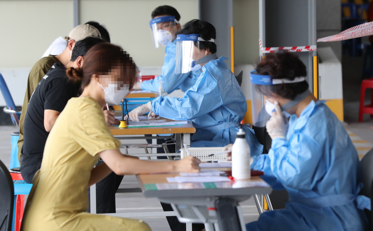 5일 오후 광주 북구보건소 선별진료소가 설치된 효죽공영주차장에서 시민들이 문진표를 작성하고 있다. [연합]