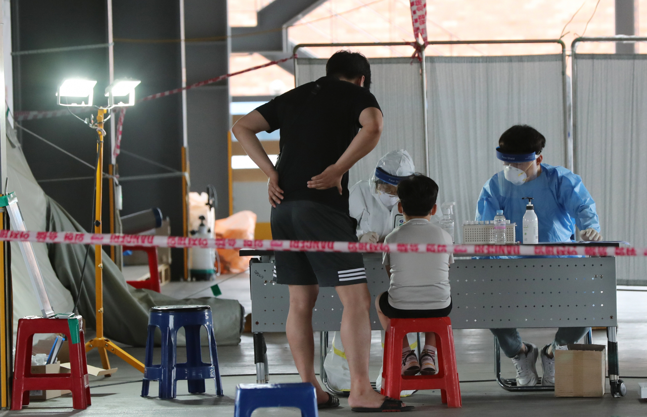 5일 오후 광주 북구보건소 선별진료소가 설치된 효죽공영주차장에서 한 학생이 부모와 함께 코로나19 검사를 받으려고 대기하고 있다. 이날 오전 광주에서는 최초로 초등학생 확진자가 나왔다. [연합]