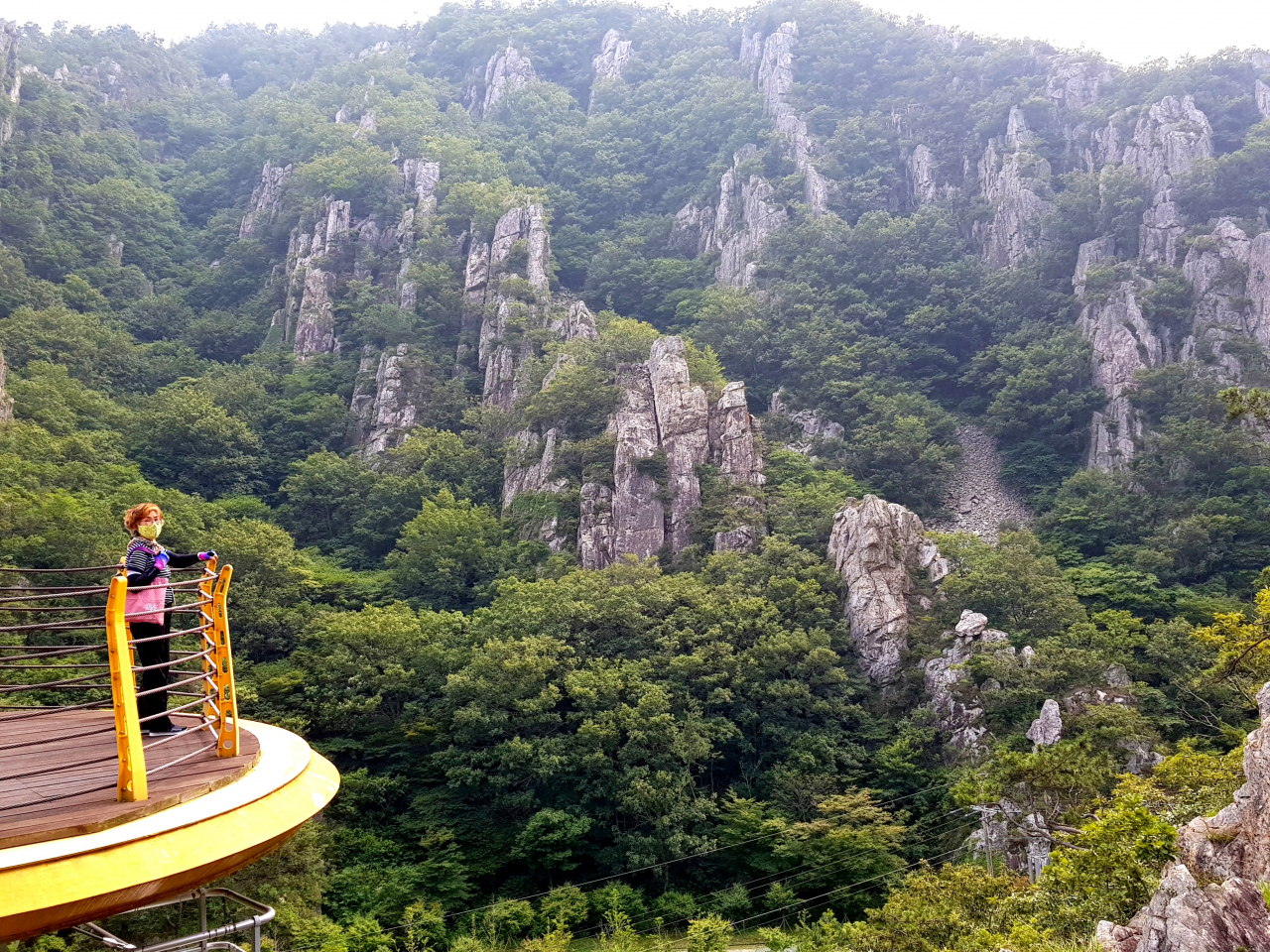 석문공원 하트 사랑 출렁다리 끝에서 본 석문산 기암괴석. 윤문숙 해설사가 석문공원을 설명하고 있다.