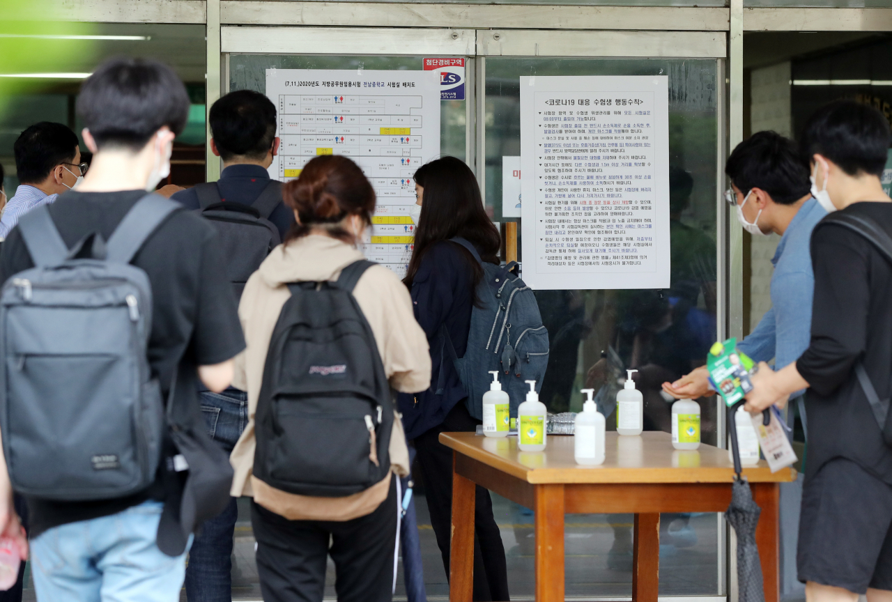 11일 오전 광주 서구의 한 중학교에 마련된 국가직 공무원 9급 필기시험장에서 수험생들이 손 소독을 하고 입실하고 있다. 최근 코로나19 확산세가 이어진 광주에서는 이날 1만2121명이 지원한 국가직 공무원 9급 필기시험이 27개 시험장, 654개 시험실에서 치러진다. [연합]