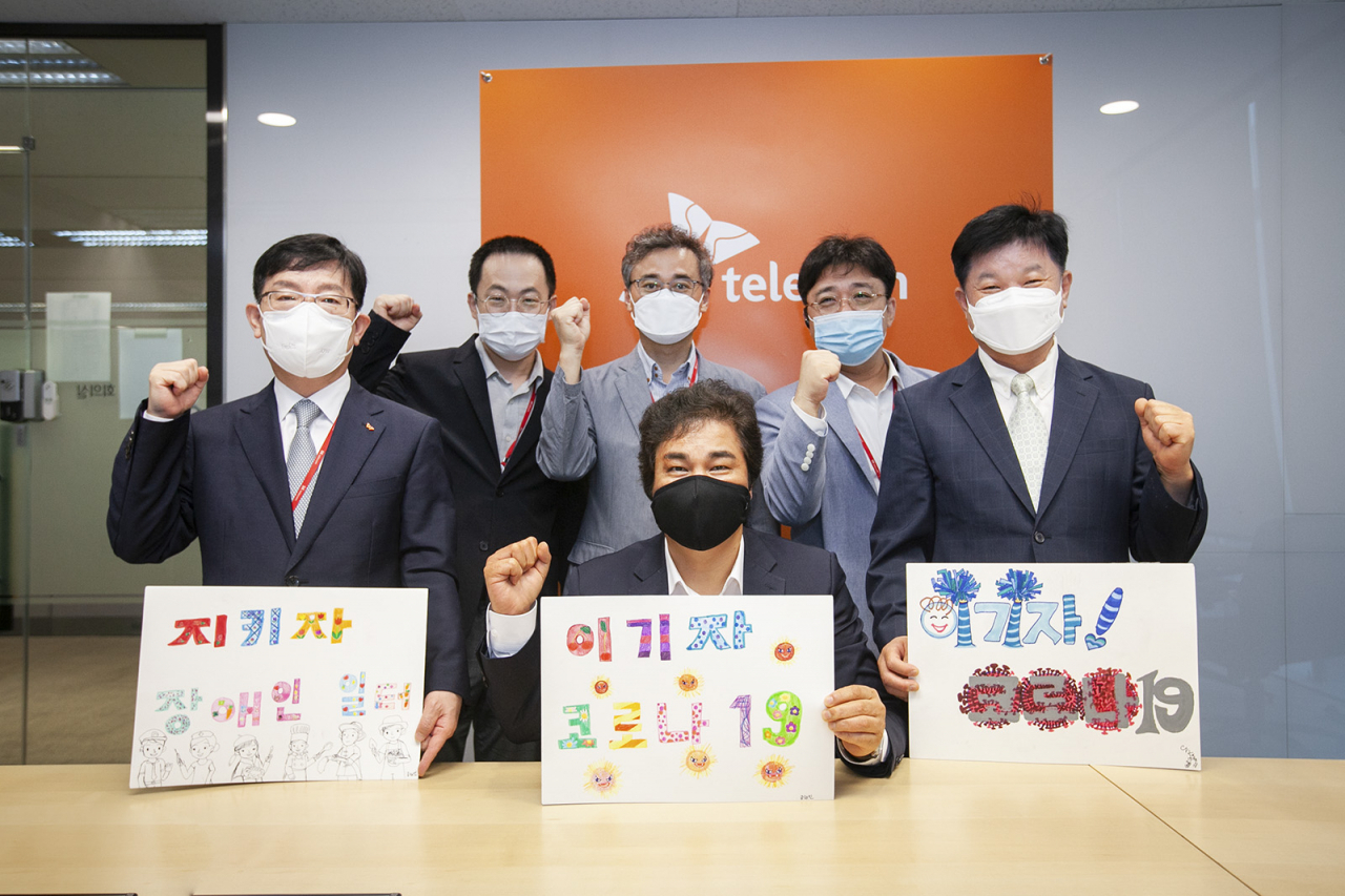 SK텔레콤은 한국장애인고용공단과 ICT기반의 장애인 일자리 플랫폼 구축을 위한 업무협약을 화상회의에서 체결했다고 12일 밝혔다. 사진은 체결식 참석자들이 한국장애인고용공단이 제작한 코로나19 극복 메시지를 들고 결의를 다지는 모습 [SK텔레콤 제공]