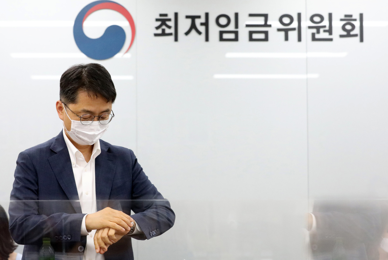 Minimum Wage Commission Chairman Park Joon-sik checks time before a general meeting of 27 members on Friday. Labor and business representatives have failed to narrow down their differences on next year's minimum wage level even though only a few days are left to reach a final decision. (Yonhap)