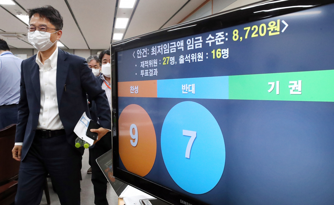 박준식 최저임금위원장(왼쪽)이 14일 새벽 세종시 정부세종청사 고용노동부에서 열린 제9차 최저임금위원회 전원회의 결과 브리핑을 마친 뒤 회의장을 나서고 있다. 이날 전원회의는 근로자위원들의 집단 퇴장으로 공익위원들이 낸 안으로 표결에 부쳐졌다. 찬성 9표, 반대 7표로 채택된 내년도 최저임금은 시급 기준 8720원으로 최종 의결됐다. ［연합］