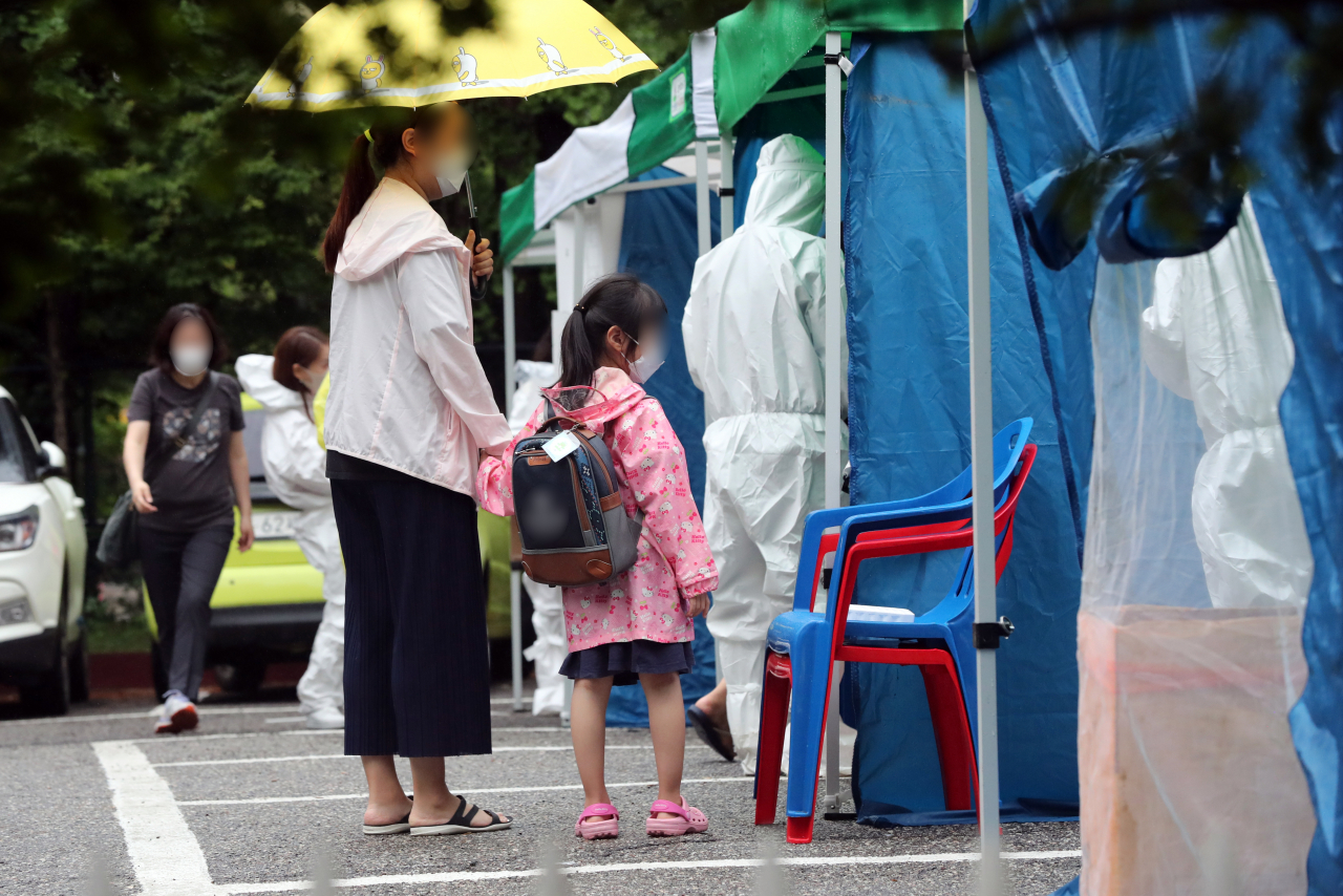 13일 오후 신종 코로나바이러스 감염증(코로나19) 선별 진료소가 차려진 경기 수원시 영통구의 한 유치원에서 원생과 보호자들이 검사 순서를 기다리며 줄을 서 있다. 연합뉴스