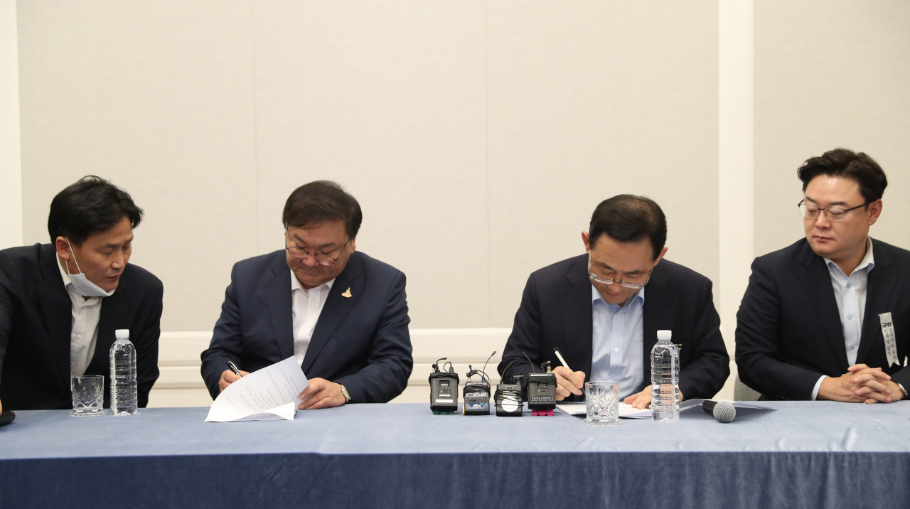 더불어민주당 김태년 원내대표와 미래통합당 주호영 원내대표가 14일 오후 서울 여의도 국회에서 개원식 등 7월 임시국회 일정 합의문에 서명하고 있다. [연합]