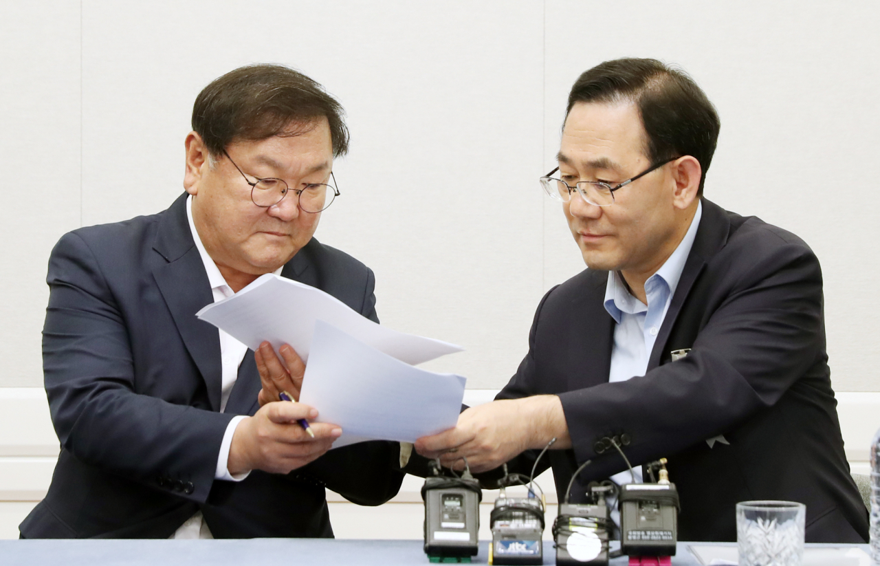 더불어민주당 김태년 원내대표와 미래통합당 주호영 원내대표가 14일 오후 서울 여의도 국회에서 개원식등 7월 임시국회 일정에 합의한 뒤 서명을 위해 합의문을 교환하고 있다. [연합]