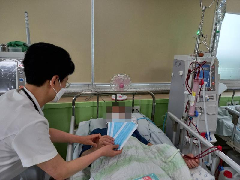 모퉁이복지재단 관계자가 후원 받은 마스크를 환자에게 전달하고 있다