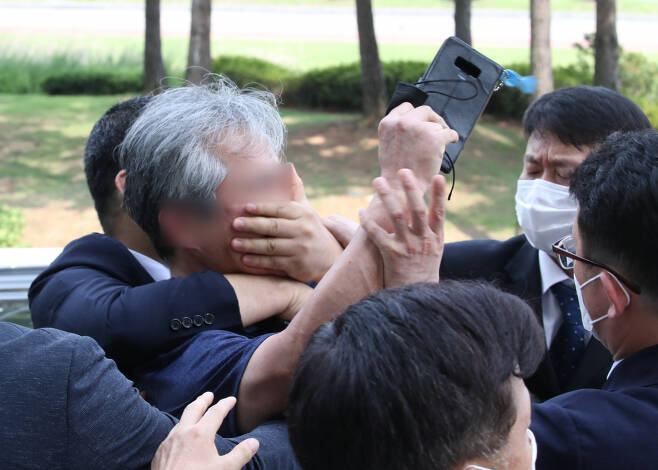 대통령 경호원들이 16일 오후 서울 여의도 국회에서 열린 제21대 국회 개원식에 참석한 문재인 대통령을 향해 신발을 던지고 소리를 지르는 시민의 입을 막고 있다. [연합]