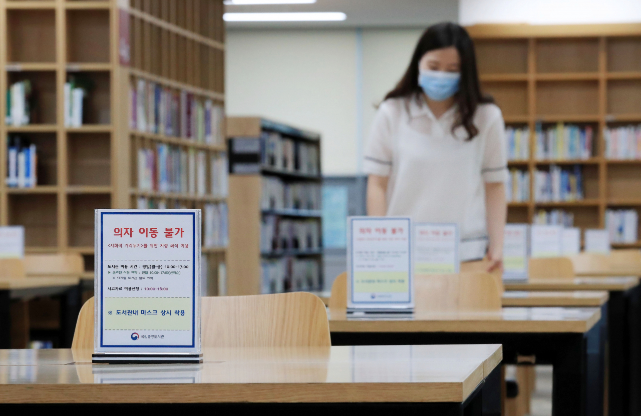 20일 서울 서초구 국립중앙도서관에서 한 직원이 신종 코로나바이러스 감염증(코로나19) 예방을 위해 좌석 간 거리를 두고 재개관 준비를 하고 있다. 코로나19 사태로 중단됐던 수도권 소재 박물관·미술관·도서관 등 국립문화예술시설의 운영이 오는 22일부터 재개된다. [연합]