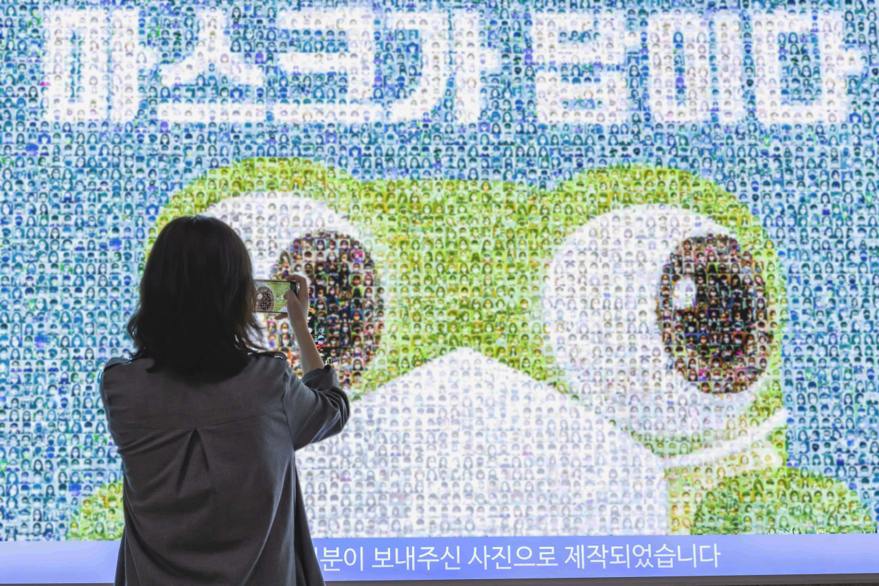 한 시민이 수원역 2층 조명광고판에 게시된 ‘마스크가 답이다’ 광고를 촬영하고 있다. [수원시 제공]