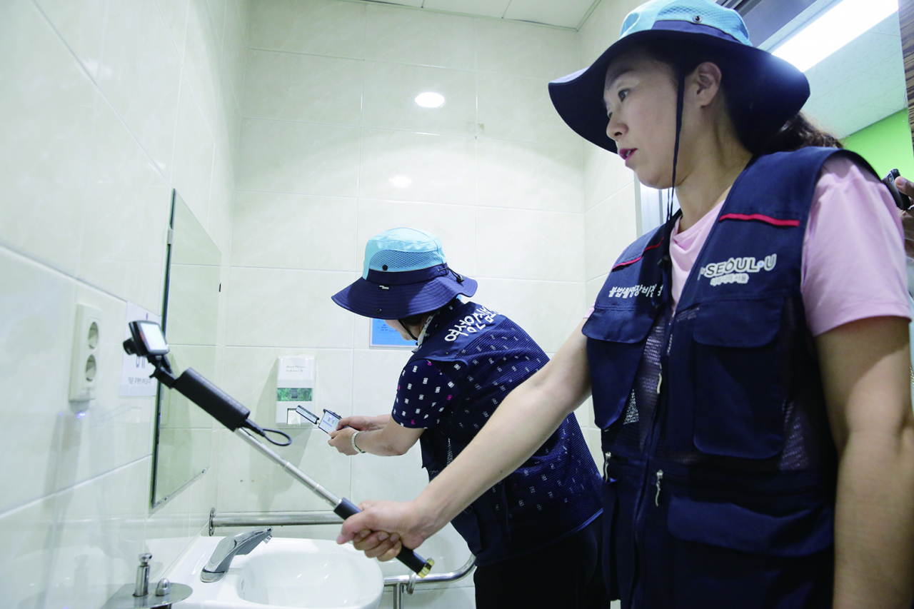 여성안심보안관이 불법촬영 카메라 탐지기를 이용해 공중화장실을 점검하고 있다. [관악구 제공]