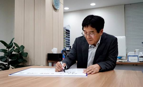 박춘원 아주캐피탈 대표가 ‘코로나19 극복을 위한 희망 캠페인 릴레이’에 동참하는 응원메세지를 전했다. 22일 오후 서울 서초구아주캐피탈 본사 집무실에서 손글씨로 직접 응원 메시지를 작성하는 모습 [아주캐피탈 제공]