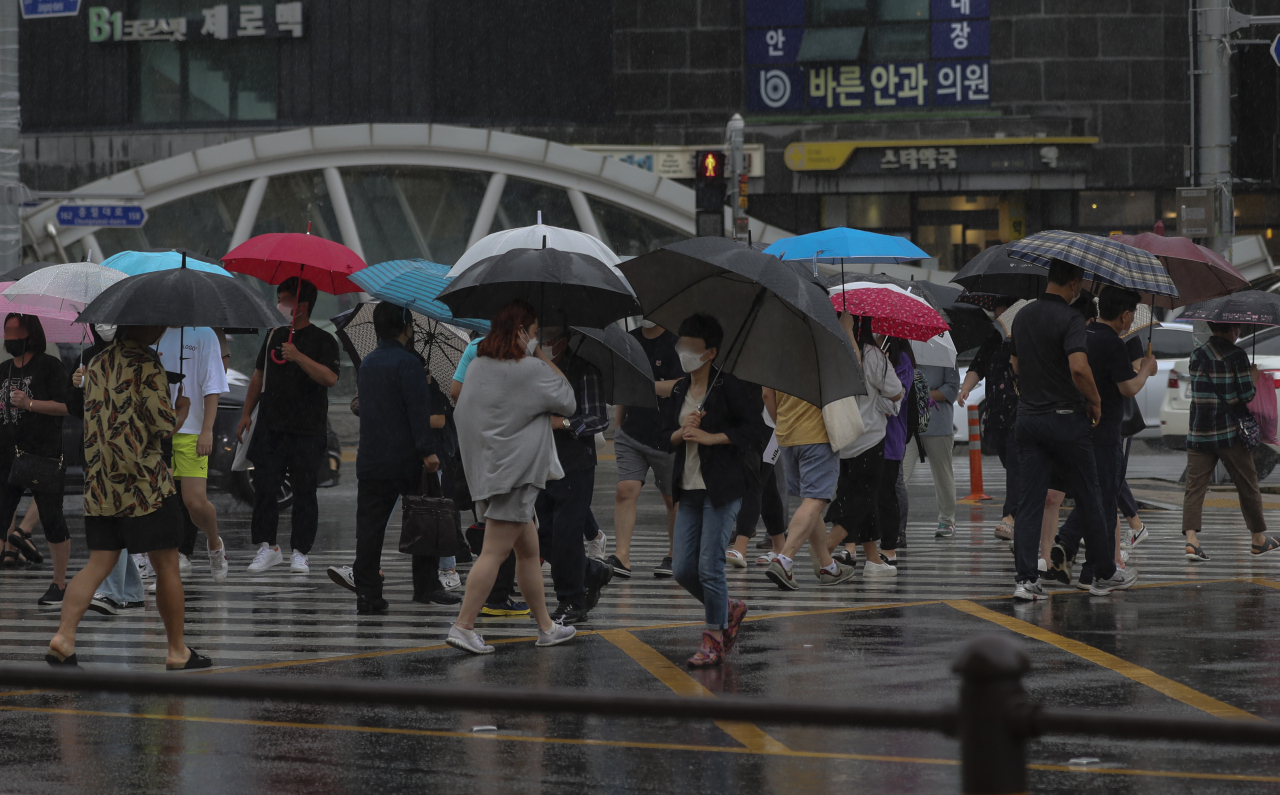 부산 전역에 호우주의보가 발효된 27일 오후 부산 동래역 앞 횡단보도에서 퇴근길 시민들이 발걸음을 재촉하고 있다. [연합]