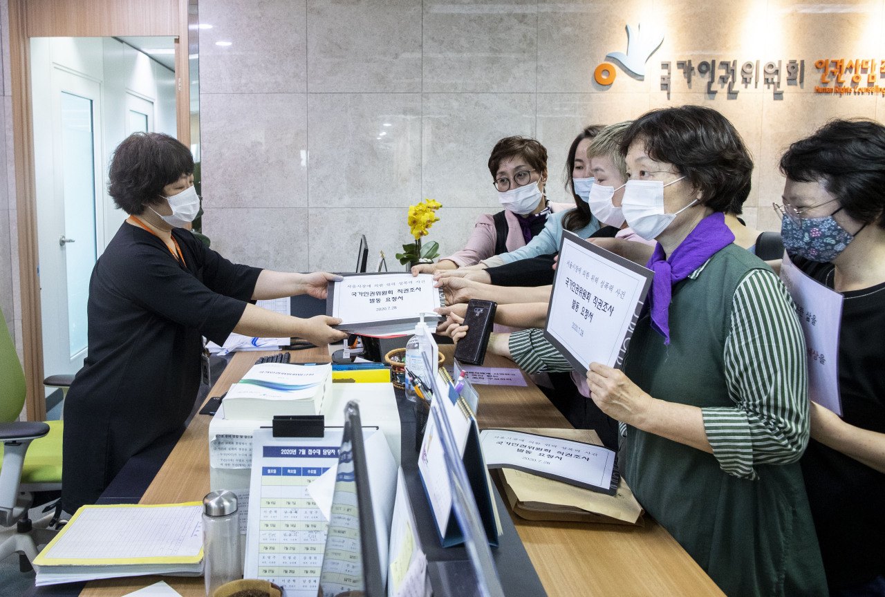 Women's rights activists submit requests for an inquiry at the reception of the National Human Rights Commission office in Seoul. (Yonhap)