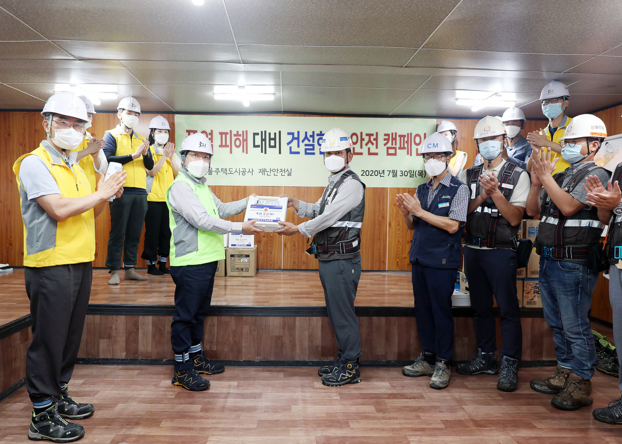 김세용 SH공사 사장(왼쪽 형광색 조끼)이 30일 위례택지개발지구 5단지 건설현장에 폭염응급키트와 이온음료를 제공하고 있다. [SH공사 제공]