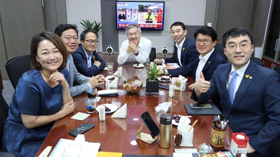 최강욱 열린민주당 대표와 황운하 더불어민주당 의원을 비롯한 '처럼회' 회원들이 30일 한 자리에 모여 웃고 있다. 최 대표 뒤에 위치한 TV에선 대전 홍수 뉴스특보가 나오고 있다. 왼쪽부터 이재정·김승원·박주민 민주당 의원, 최 대표, 김용민·황운하·김남국 민주당 의원. [최강욱 대표 페이스북 페이지 캡처]