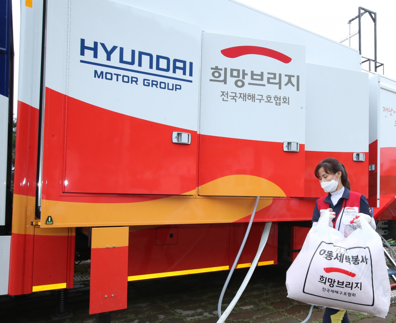 최근 폭우와 침수로 피해를 입은 경북 영덕군 강구면 강구시장에서 현대차그룹의 세탁구호차량과 함께 희망브리지 전국재해구호협회 자원봉사자들이 세탁 봉사활동을 하고 있다. [현대차그룹 제공]