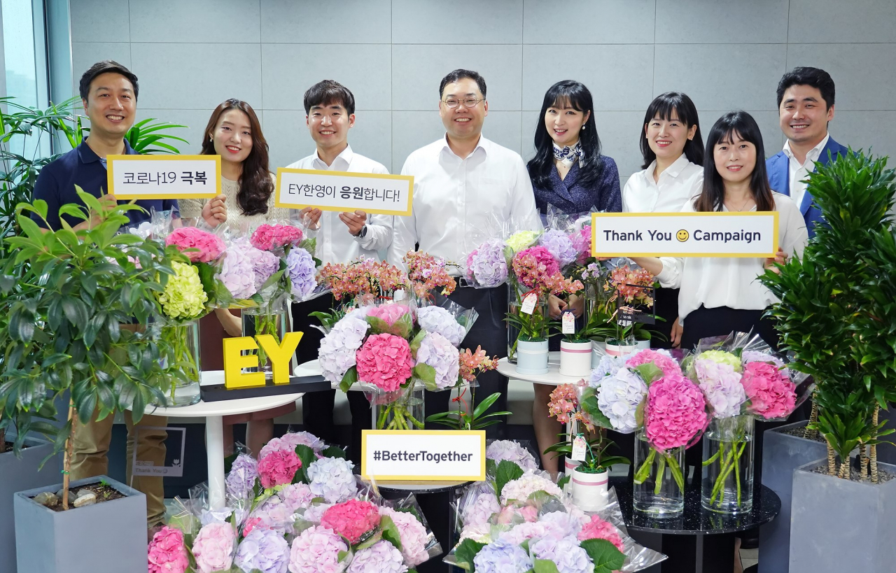 EY한영 ‘땡큐 스마일 캠페인(Thank you Smile Campaign)’에 참여한 EY한영 임직원들이 박용근 대표이사(왼쪽 넷째)와 함께 코로나19 극복 메시지를 담은 플래카드를 들고 기념촬영을 하고 있다. [EY한영 제공]