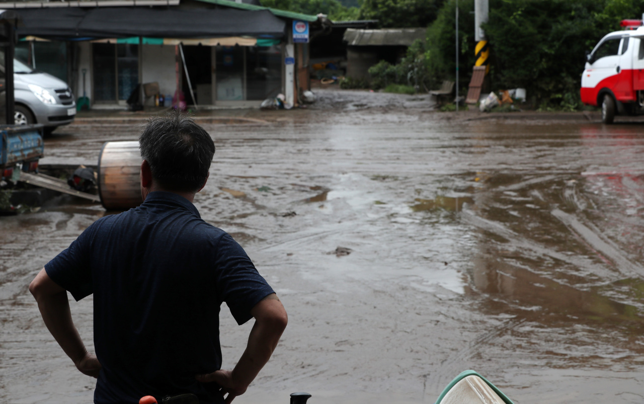 A man in Cheorwon County, Gangwon Province, stares at his village's flooded road Monday after more than 300 millimeters of rain poured in the region overnight. (Yonhap)