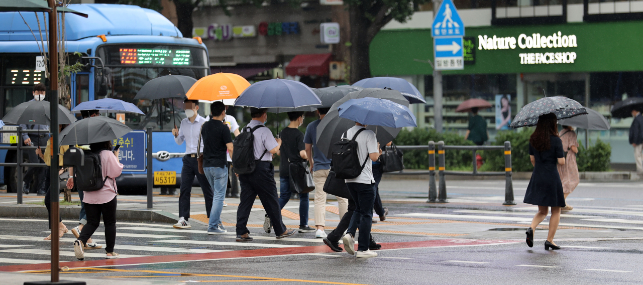 지난 5일 오전 서울 종로구 광화문 세종대로사거리에서 우산을 쓴 출근길 시민들이 발걸음을 옮기고 있다. [연합]