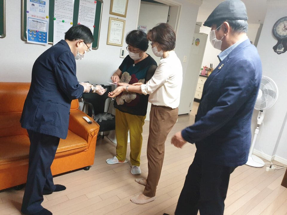 경로당에서 노인들 손목 안쪽에 체온계를 붙이고 있는 대한노인회 군포시지회 회원들. [군포시 제공]