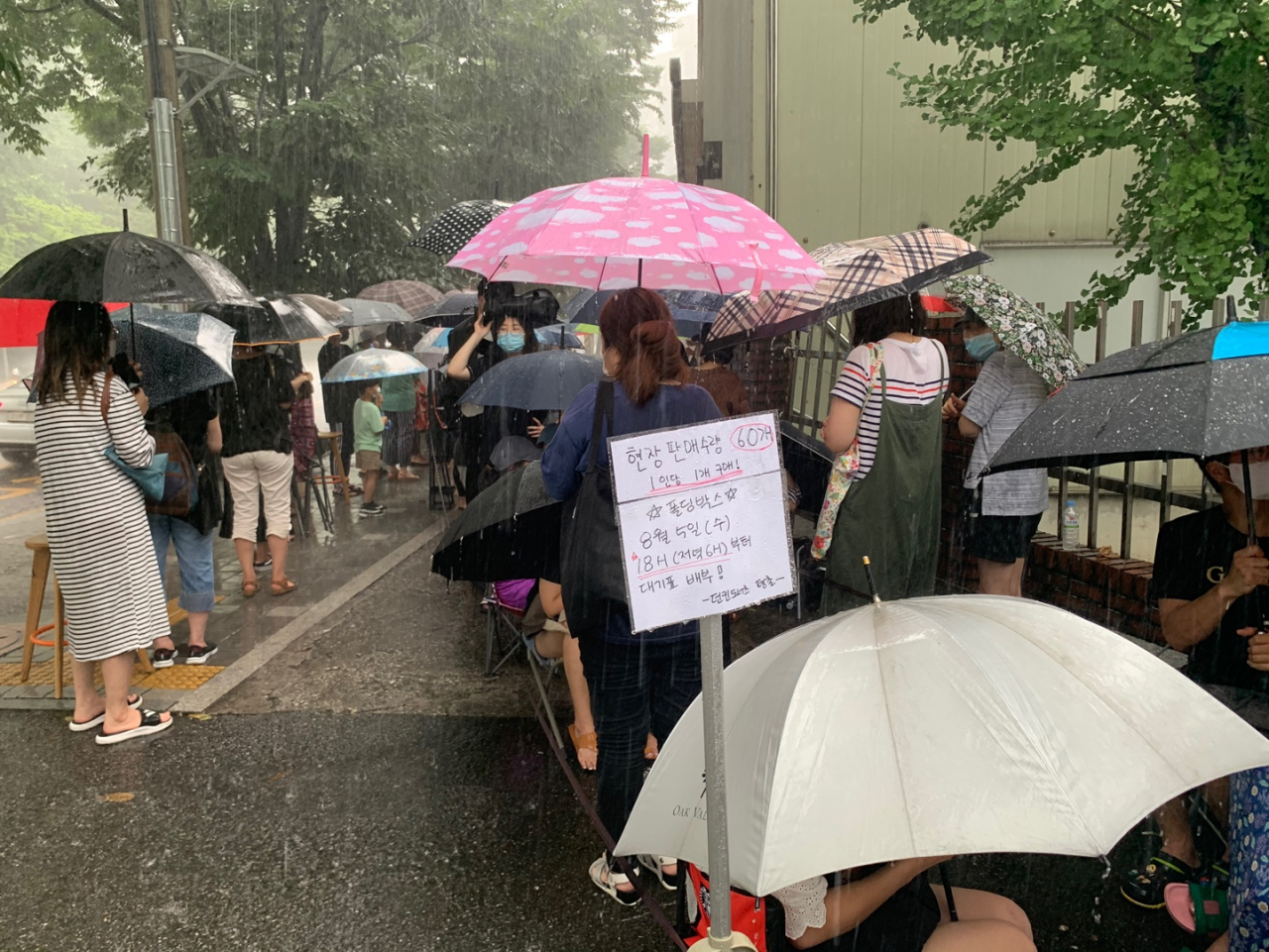 지난 5일 4시께 경기도 안양시 던킨도너츠 평촌점에서 캠핑용품 굿즈 폴딩박스를 구매하기 위해 빗속에서 사람들이 줄 서 있다. [사진=김빛나 기자]